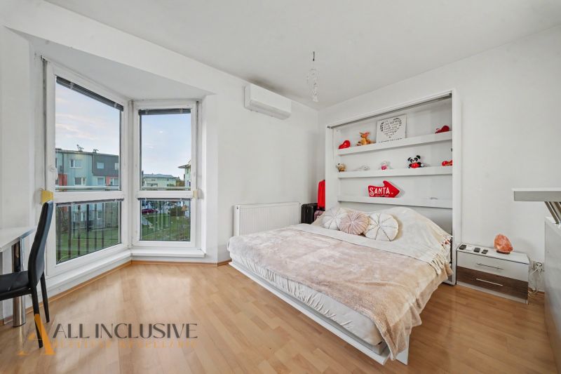 Interior of a 1-room apartment with a bed, shelf, and floor with wood decor.