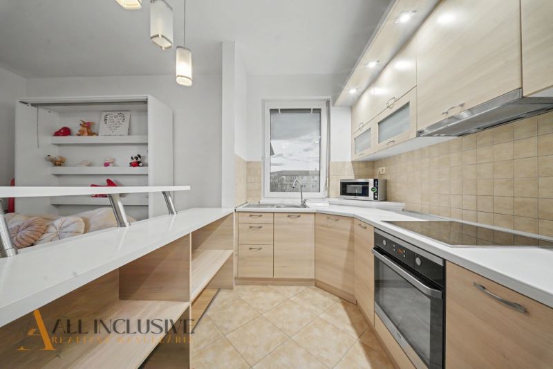 A kitchen in a studio apartment with light-colored cabinets and built-in appliances.