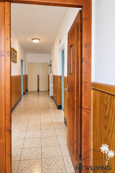 A hallway of a family house with wooden paneling, floor with decorative tiles.