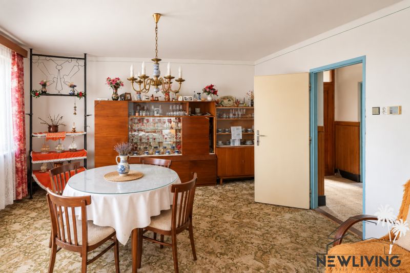 Dining room in a family house with wooden furniture, carpet, chandelier, and decorations.