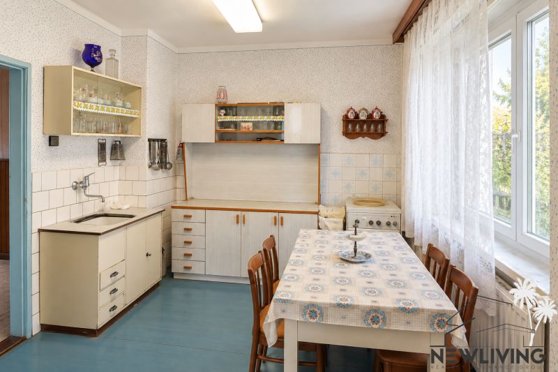 A kitchen in a family house with older furniture, a blue floor, and a white tablecloth.