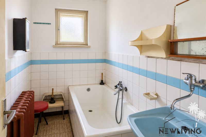A bathroom of a family house with white tiles and a blue sink.