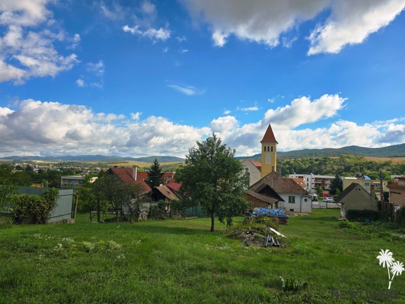 A view of family houses in the village of Banka, Topoľčianska Street with a church in the background.
