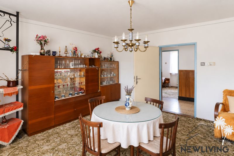 Dining room in a family house with a chandelier, round table, and a display cabinet with glasses.