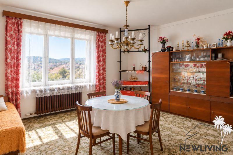 A dining room in a family house with floral curtains and a glass cabinet.