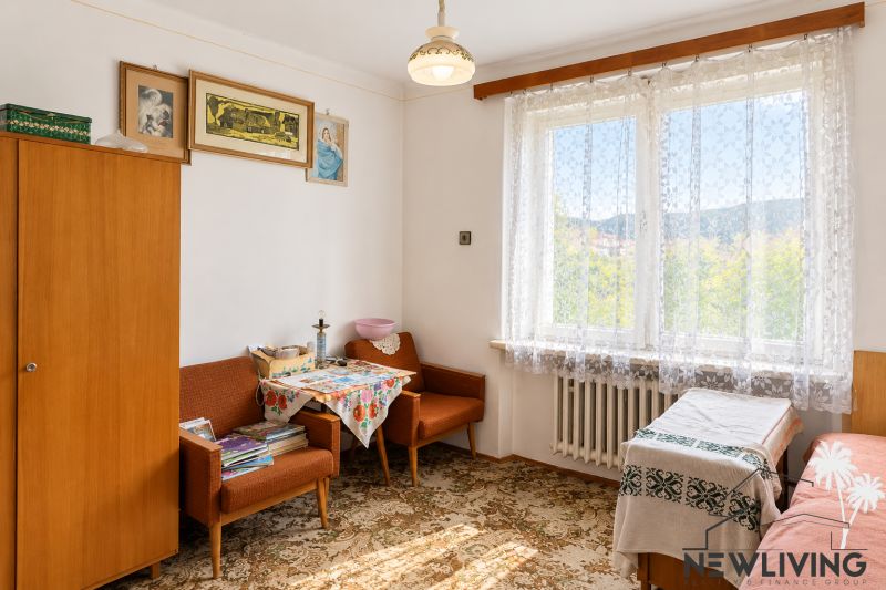 A room in a family house with vintage furniture, decorative paintings, and lace curtains.