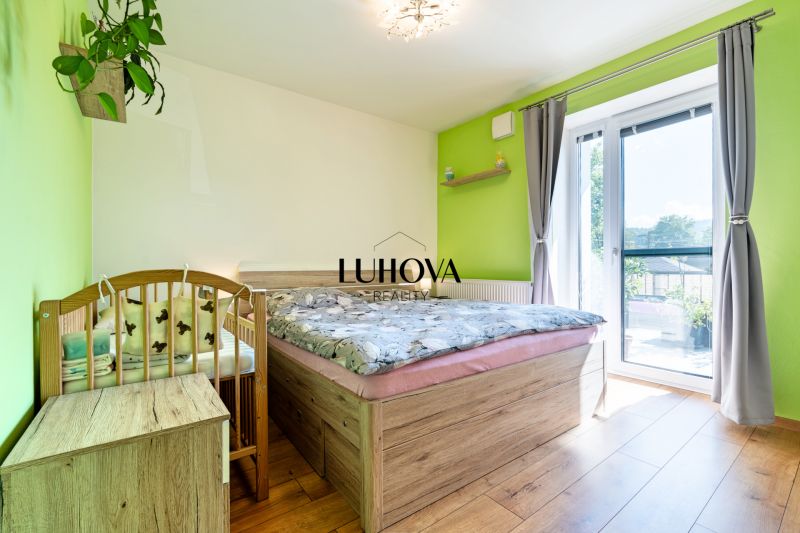 A bedroom in a 3-room apartment with a bed, a baby crib, and a floor with a wooden decor.