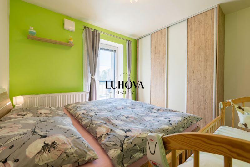 Bedroom in a 3-room apartment with a green wall, floral bedding, and a wardrobe.