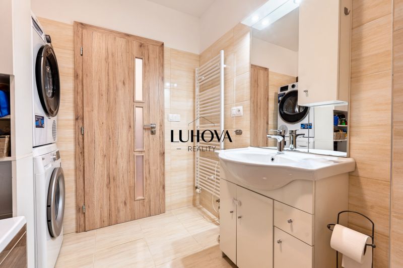Bathroom with a washing machine and dryer, cabinet under the sink, and floor with wood decor.