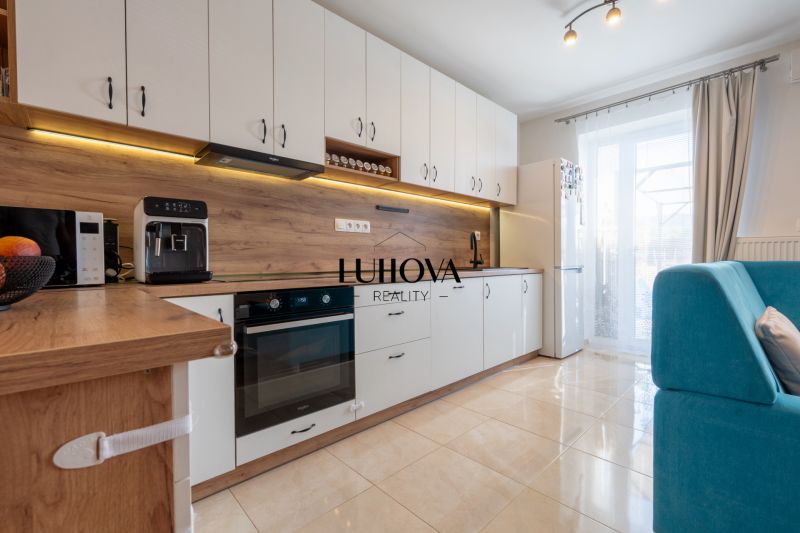 A kitchen in a 3-room apartment with white cabinets and a wood-patterned floor.