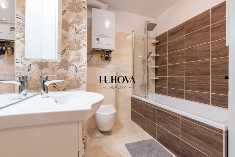 A bathroom with a bathtub and tiles in a 3-room apartment, floor with wooden decor.