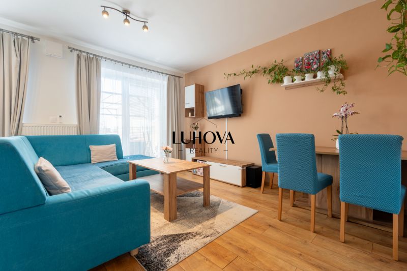 A bright living room in a 3-room apartment with a blue sofa, wooden decor, and a TV on the wall.