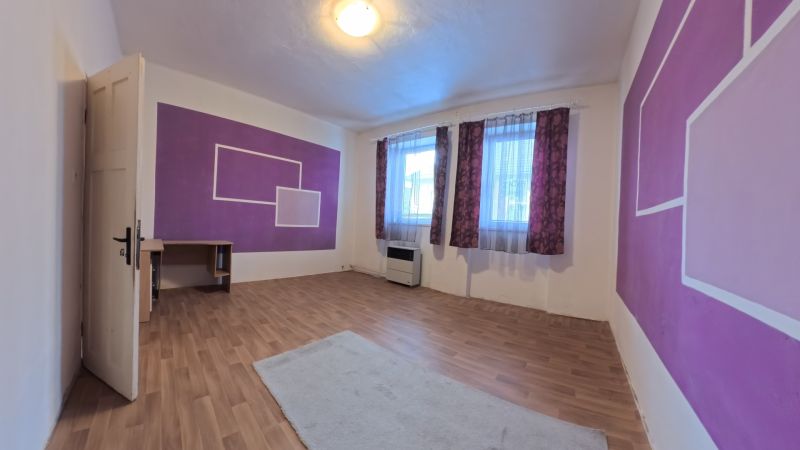 A room in a family house with purple walls and a wooden-patterned floor.
