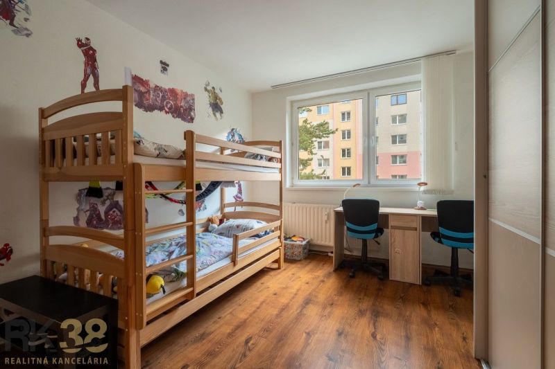 Children's room with a bunk bed and a desk in a 3-room apartment with a wooden decor floor.