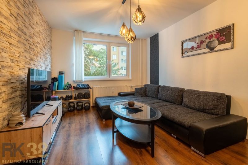 Living room in a 3-room apartment with a sofa, table, and floor with a wooden decor.