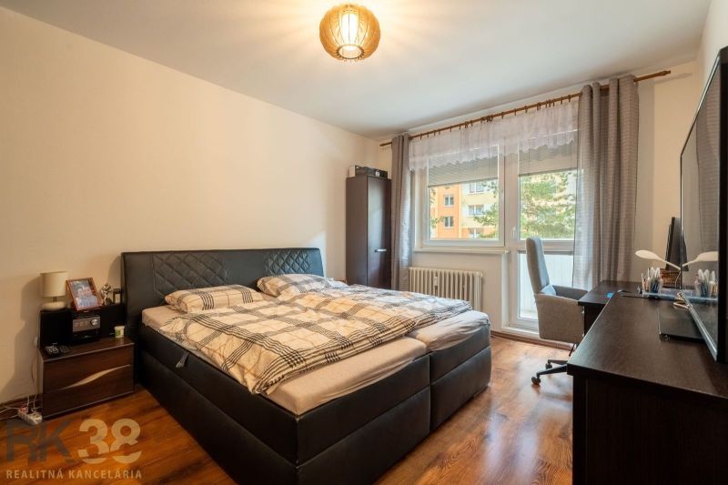 A bedroom in a three-room apartment with a wood-patterned floor and a bunk bed.