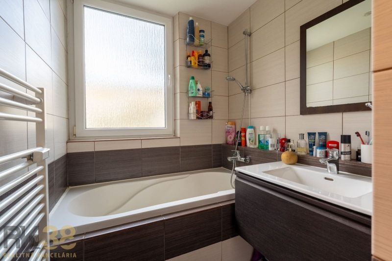 A bathroom with a bathtub and a sink in a 3-room apartment with a lot of toiletries.