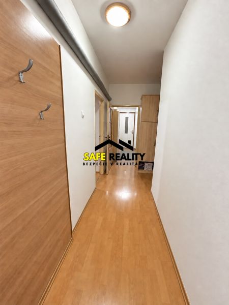 A hallway in a one-room apartment with a wooden decor floor and a built-in wardrobe.