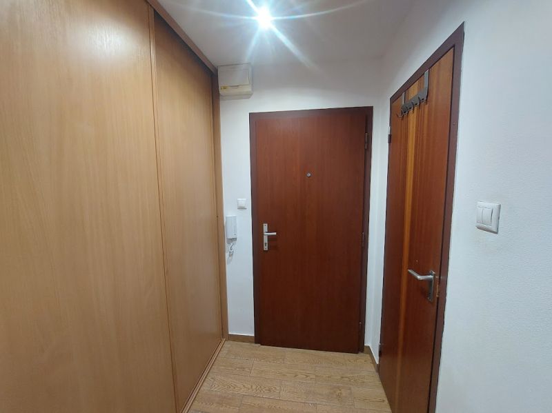 A hallway in a one-room apartment with a wooden decor floor and wooden doors.