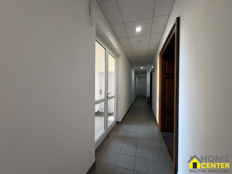 A corridor with tiles and white walls leads to other offices.