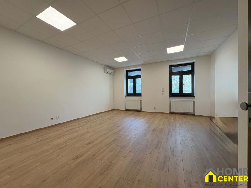 A spacious office with white walls and a wooden decor floor.