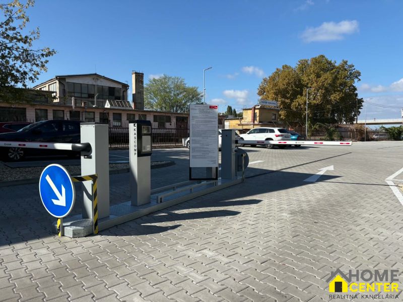 Fenced entrance to the office parking lot in Komárno with an automatic barrier.