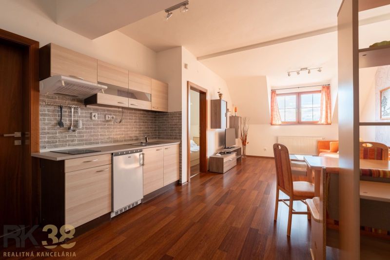A kitchen in a 2-room apartment with a wood-patterned floor and a dining table.