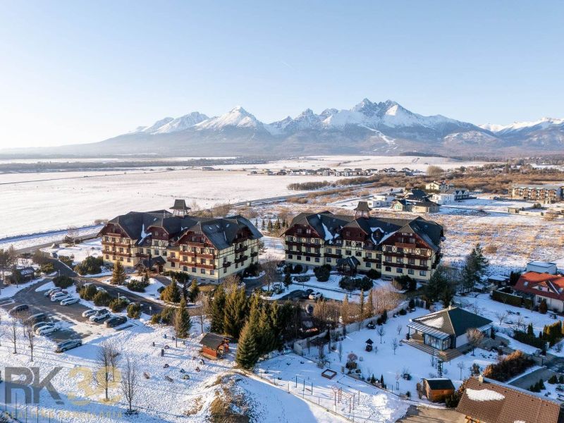 Winter scenery in Veľká Lomnica with a view of the Tatras and buildings offering 2-room apartments.