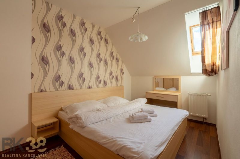 A bedroom in a two-room apartment with a bed, wallpaper, and a wooden decor floor.