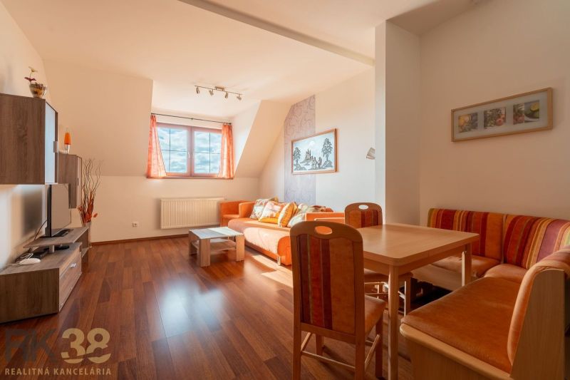 Living room of a two-room apartment with a wooden decor floor and orange furniture.