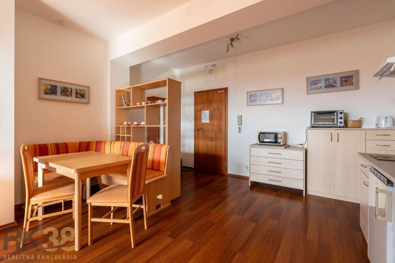 Living room in a two-room apartment with a dining table and a wooden decor floor.