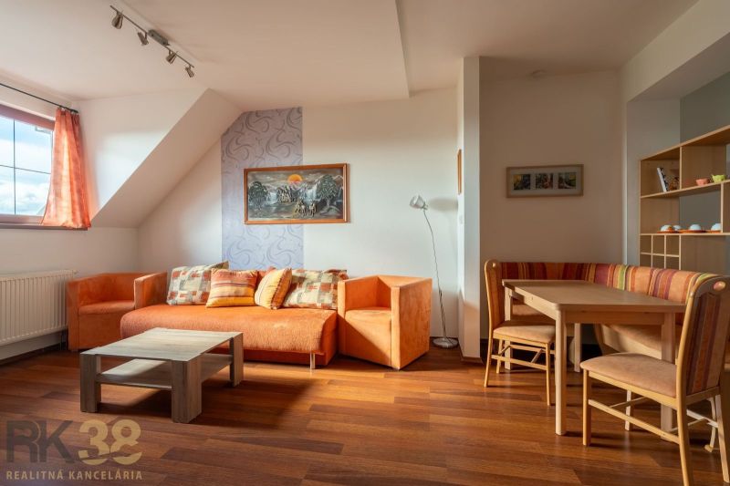 Living room in a two-room apartment with orange furniture and a wooden decor floor.