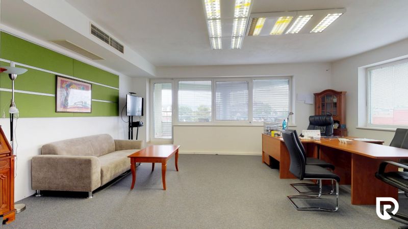 Offices with a sofa, desk, chairs, and a green wall, furnished for work purposes.