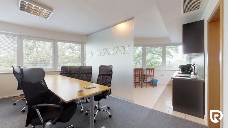 Interior of an office with large windows, a conference table, and a kitchenette.