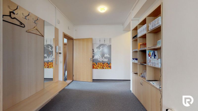 The interior of an office with carpet flooring, open shelves, and hooks for hanging clothes.