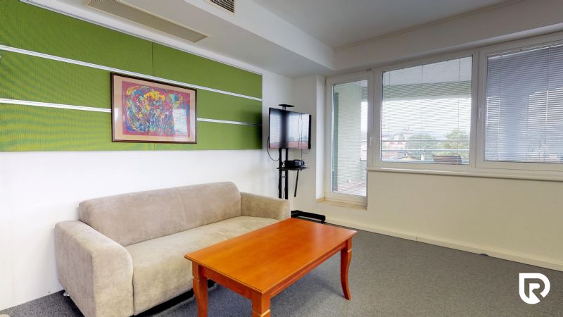 Comfortable seating in the office with a picture and a television on the wall.