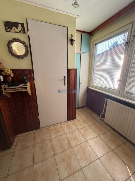 Tiled entrance hall in a family house with wooden wall paneling and a mirror.