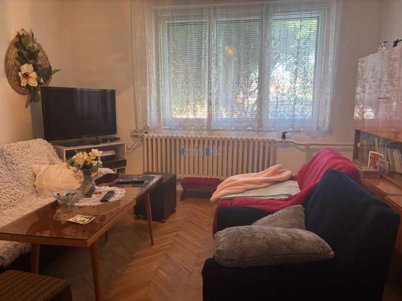 Living room in a family house with wooden floor decor, sofa, and television.