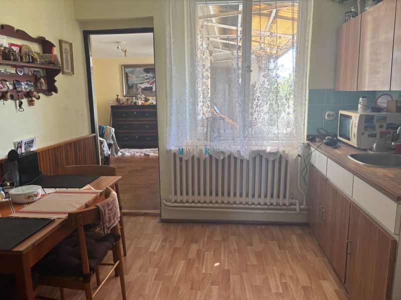 A kitchen in a family house with a wooden decor floor, curtains, and furniture.