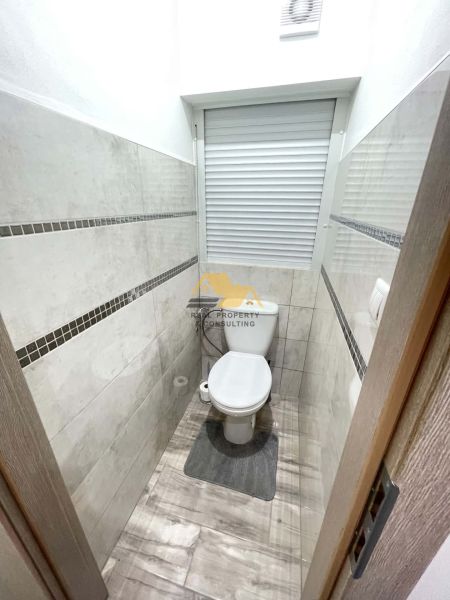 A bathroom with tile cladding and a wooden decor floor in a studio apartment.