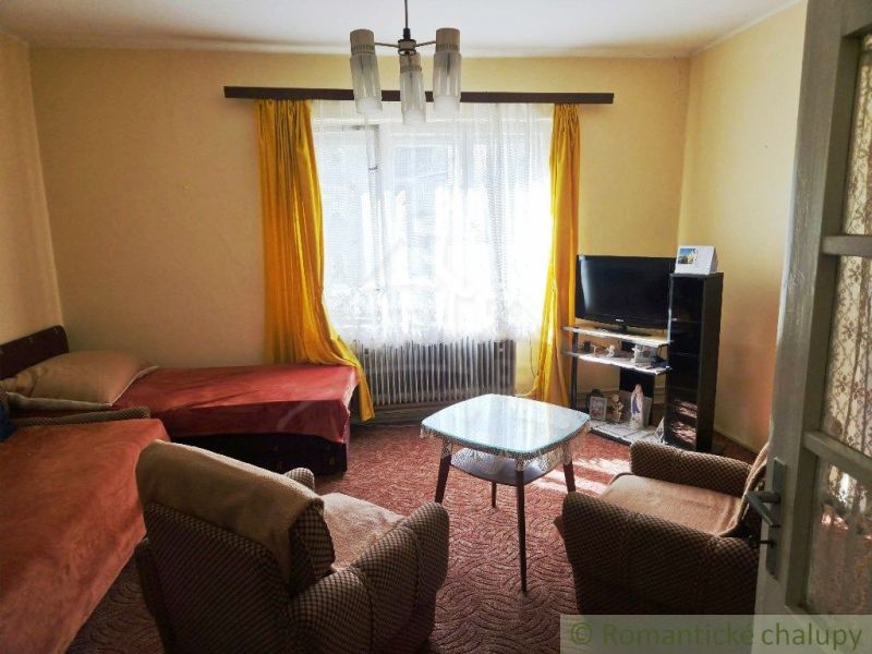 A living room in a family house with a bed and a television, yellow curtains.