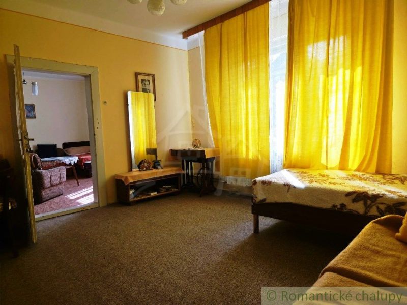 A room in a family house with yellow curtains and simple furniture.