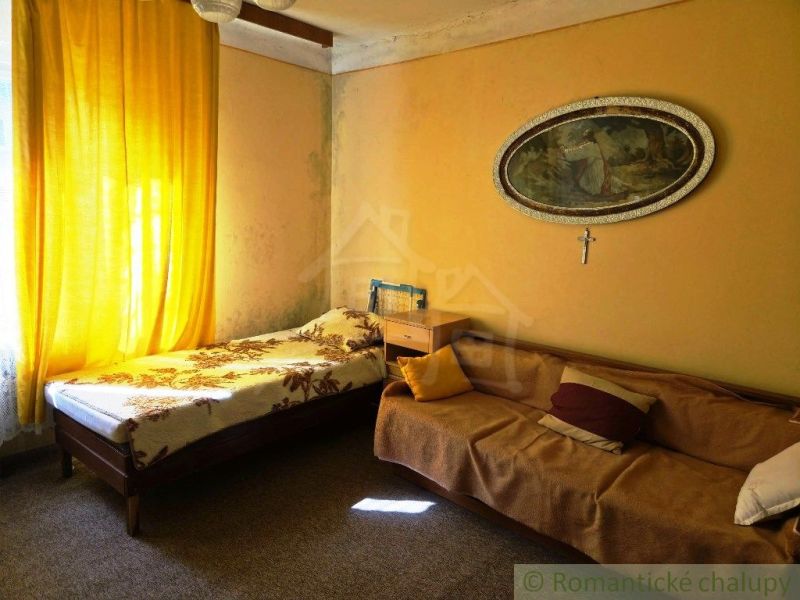 A room in a family house with a bed, a sofa, and yellow curtains.