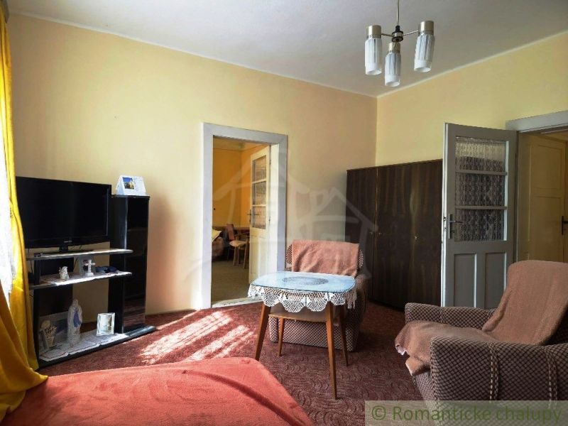 A living room of a family house with comfortable armchairs and a TV on a stand.