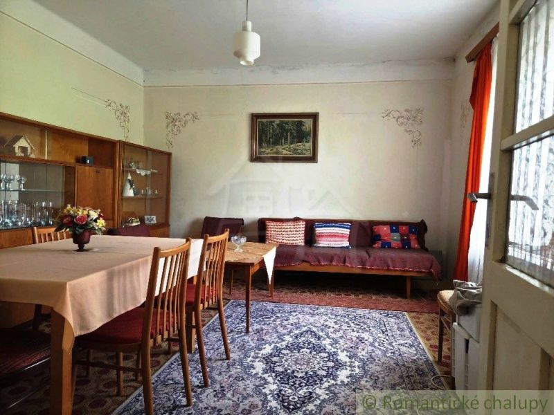 The dining room of a family house with a carpet, wooden furniture, and decorative curtains.