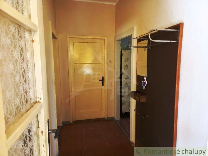 A hallway of a family house with a coat rack, a mirror, and doors in warm tones.