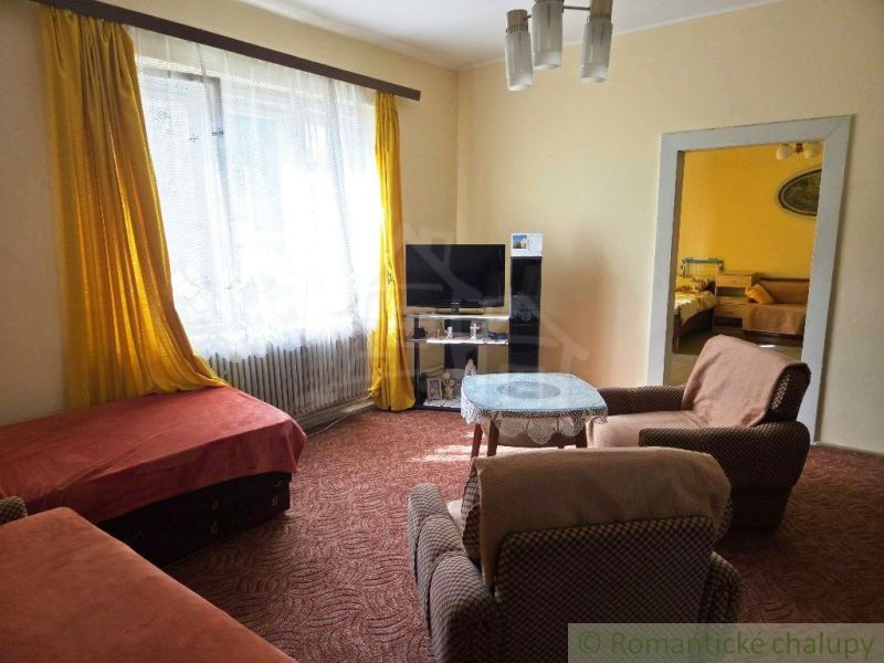 A living room of a family house with carpets, armchairs, and yellow curtains.