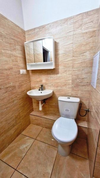 A bathroom in a studio apartment with tiles and a mirrored cabinet above the sink.
