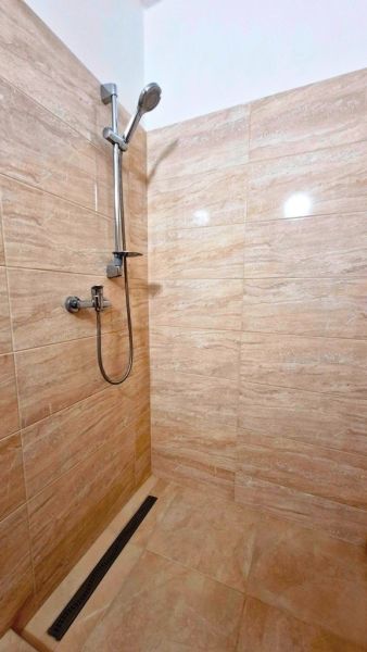 Shower corner with beige tiles in a studio apartment, subtle color scheme.