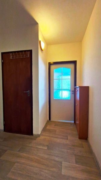 In the studio apartment, there is a narrow hallway with a wood-patterned floor and wooden doors.